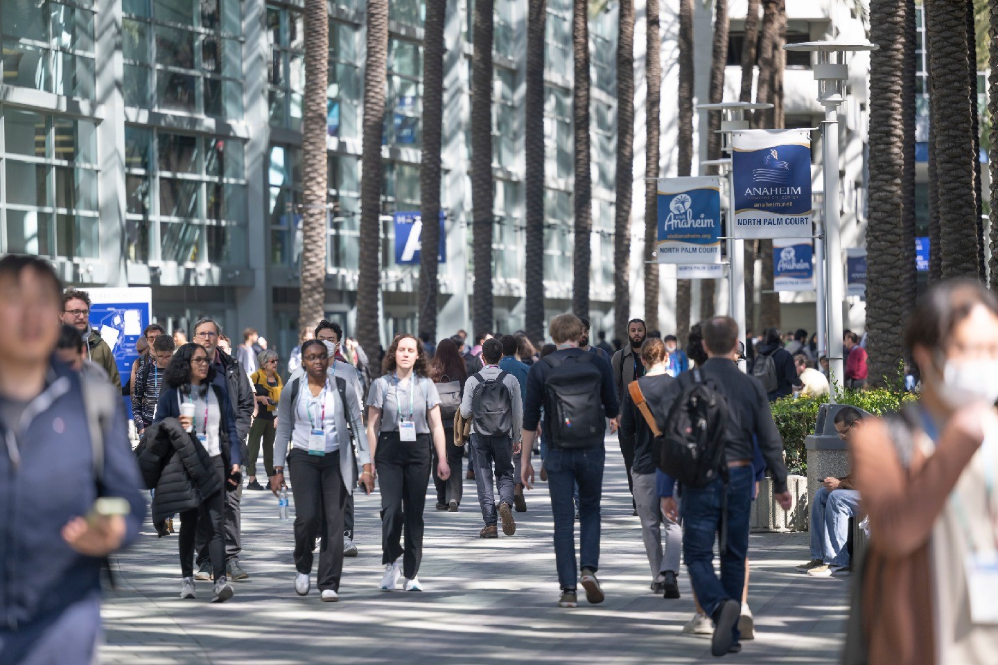 People wearing conference badges and walking under banners for the Anaheim Convention Center.