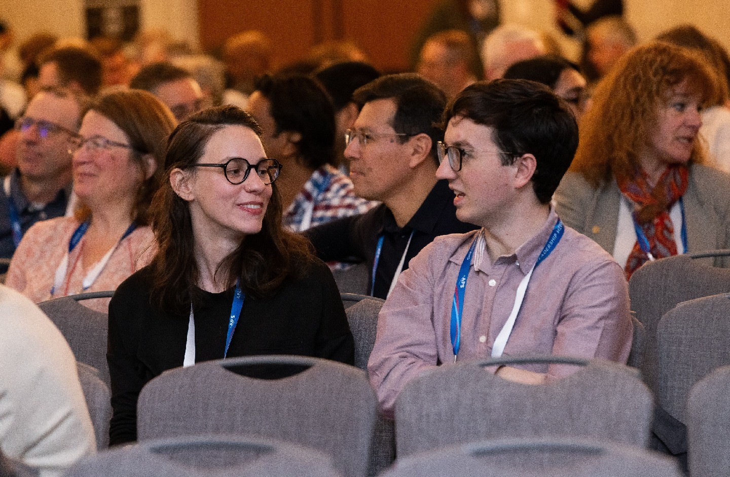 Two students speaking while seated in an auditorium