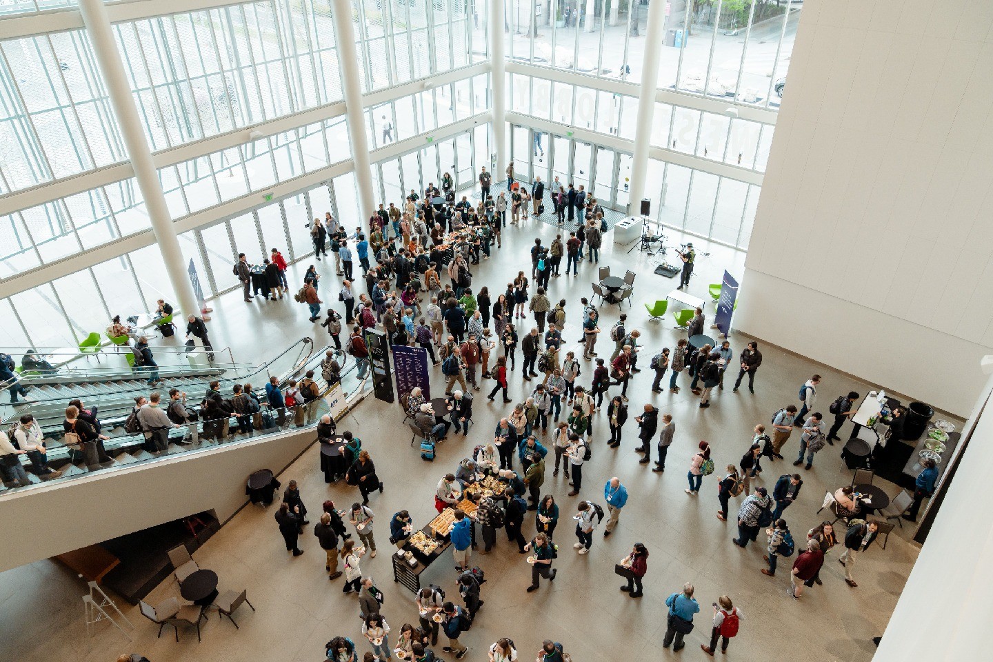 High angle view of people gathering at tables and signage inside a building.