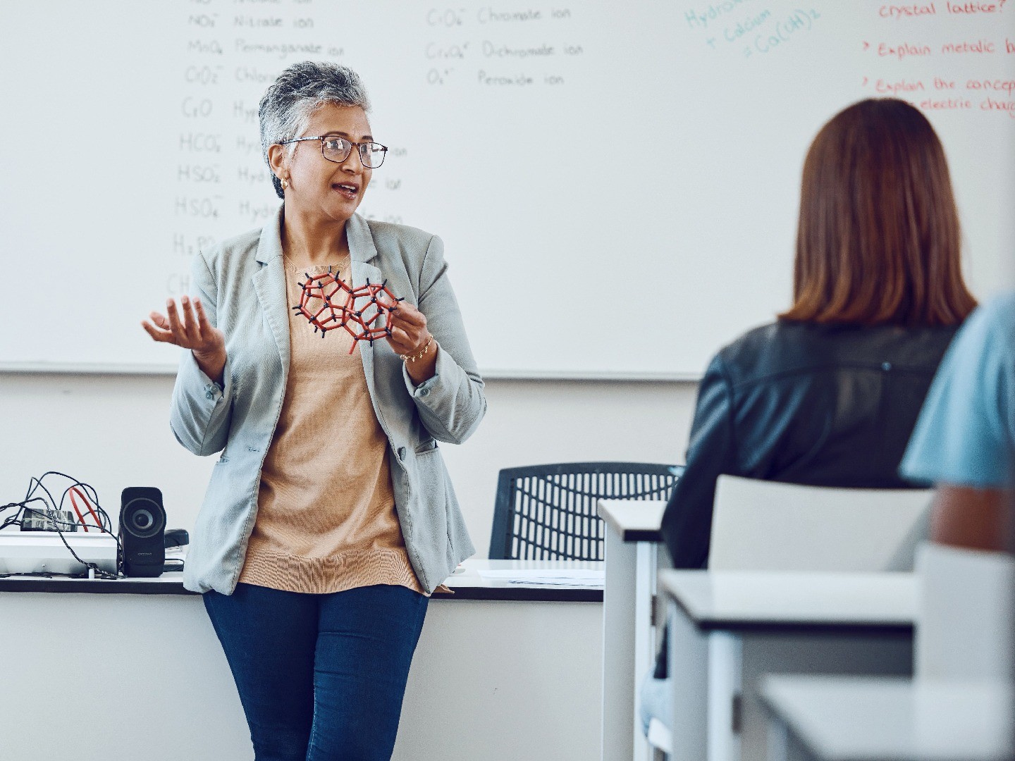 A teacher holding a model of molecules while teaching a class