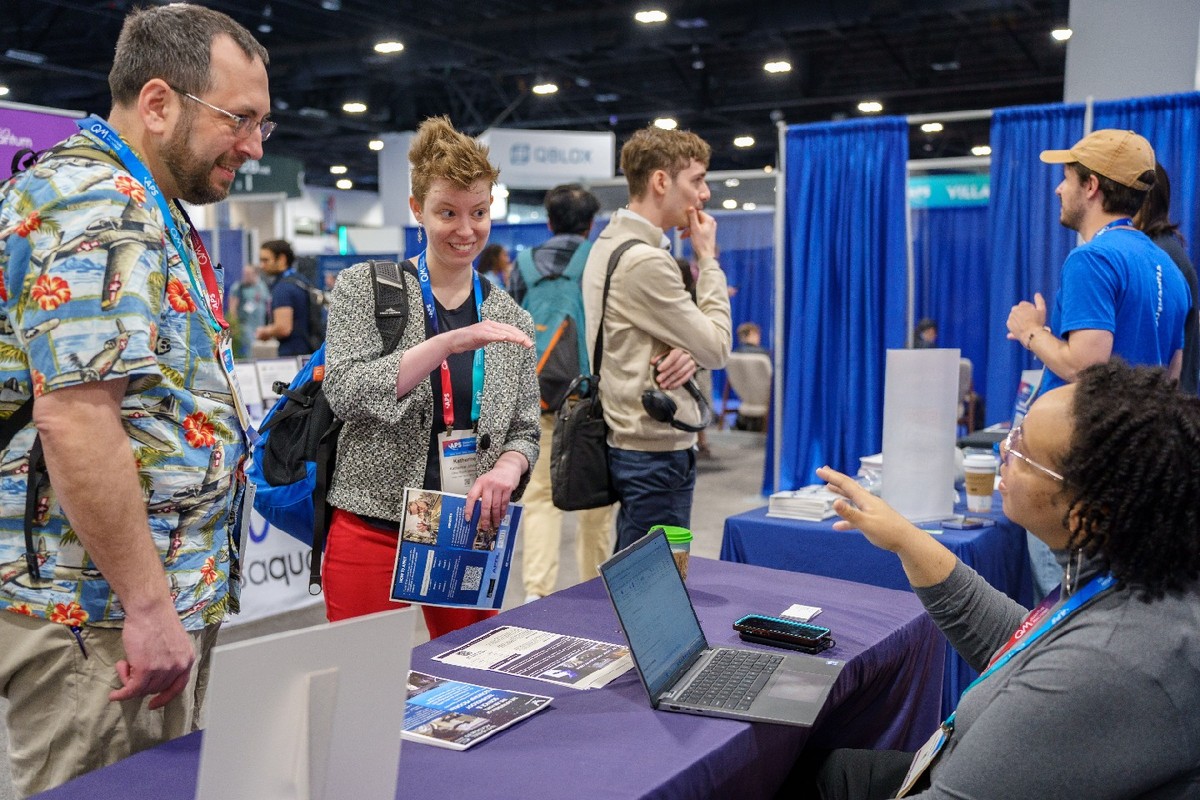 Conference attendees in conversation with participants at information tables.