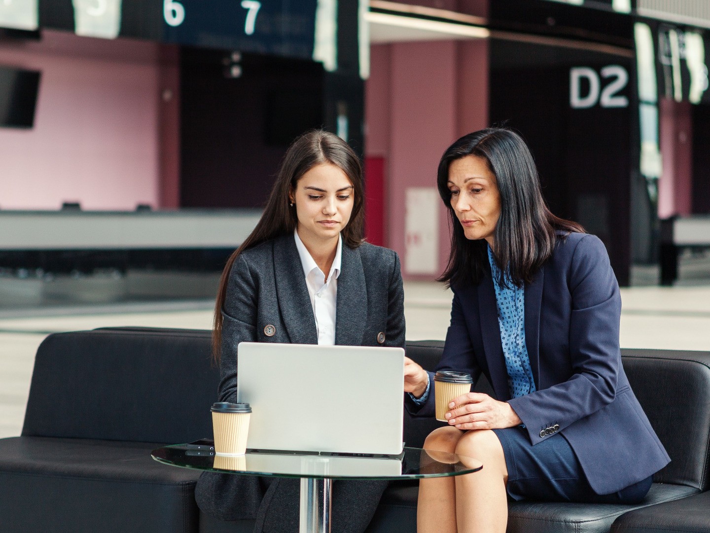 Mature professional woman advising a younger colleague during a coffee break