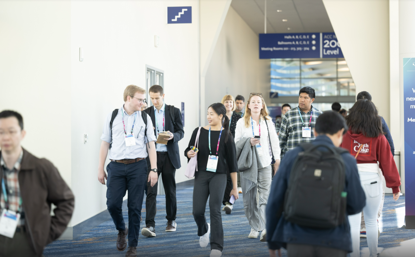 A crowd of attendees wearing badges and walking in a hall