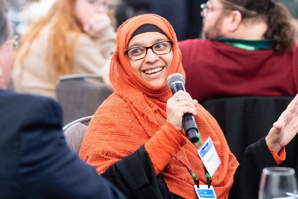 A woman wearing an orange hijab speaking into a microphone