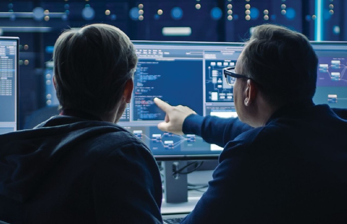 A student and professor looking at a series of computer screens