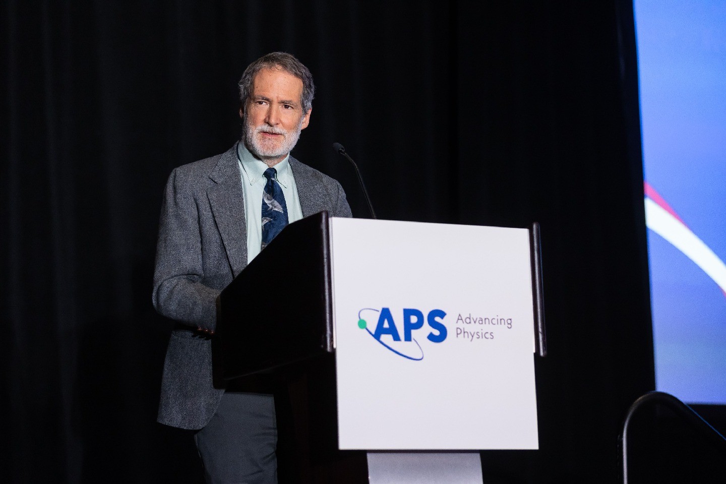 2026 APS President Brad Marston speaking at a podium