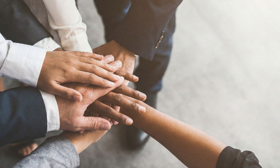 A diverse group of people putting their hands together, representing teamwork and collaboration