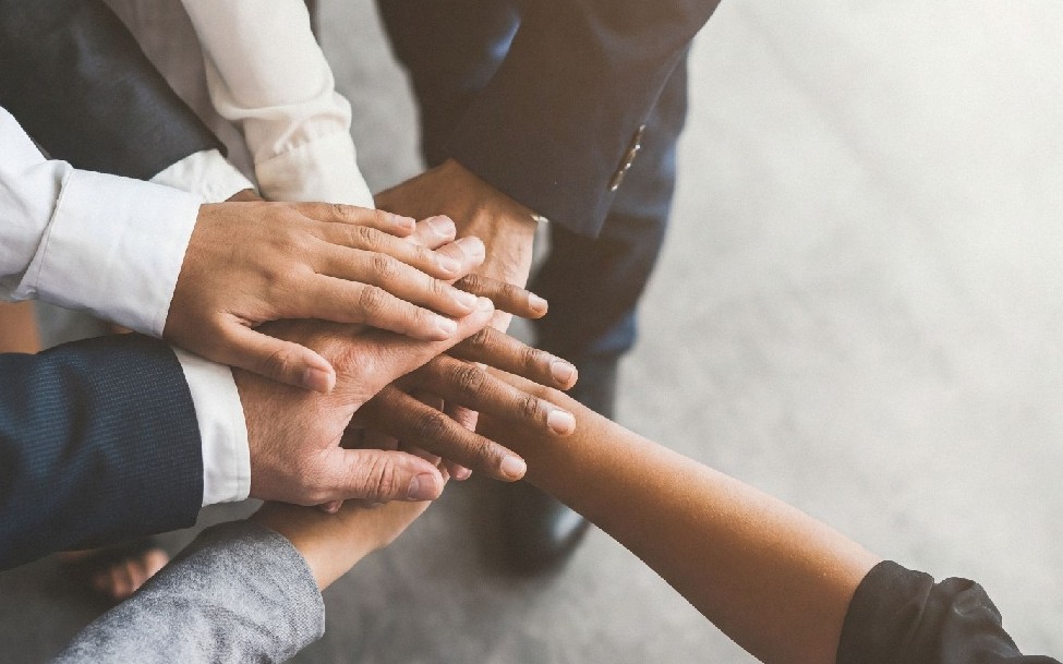 A diverse group of people putting their hand together to represent teamwork and collaboration