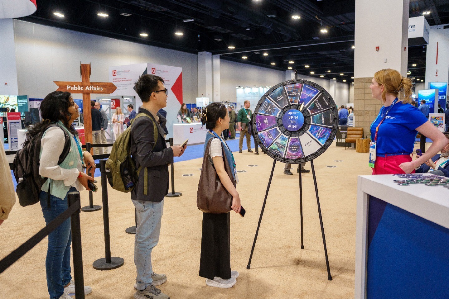 People forming a line at an expo environment to spin a wheel that says "Spin to Win." 