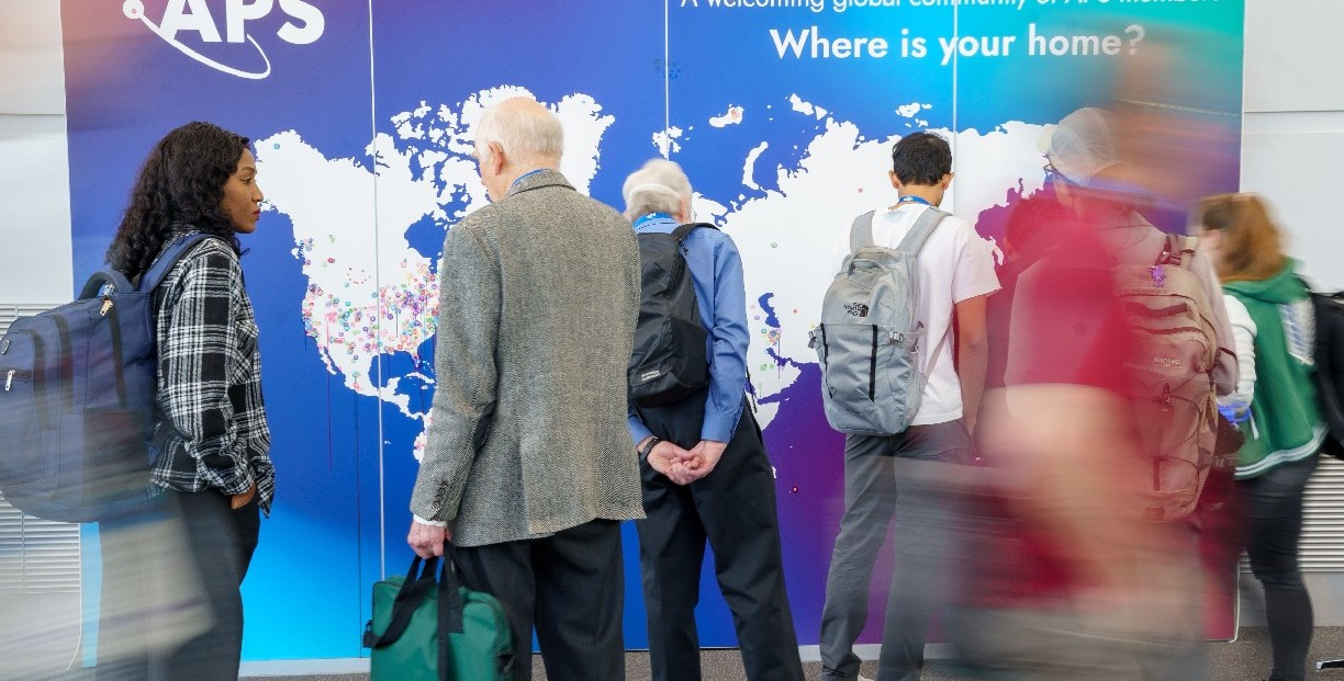Global Physics Summit attendees standing in front of a world map