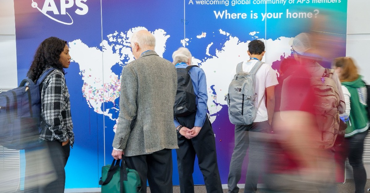 Global Physics Summit attendees standing in front of a world map