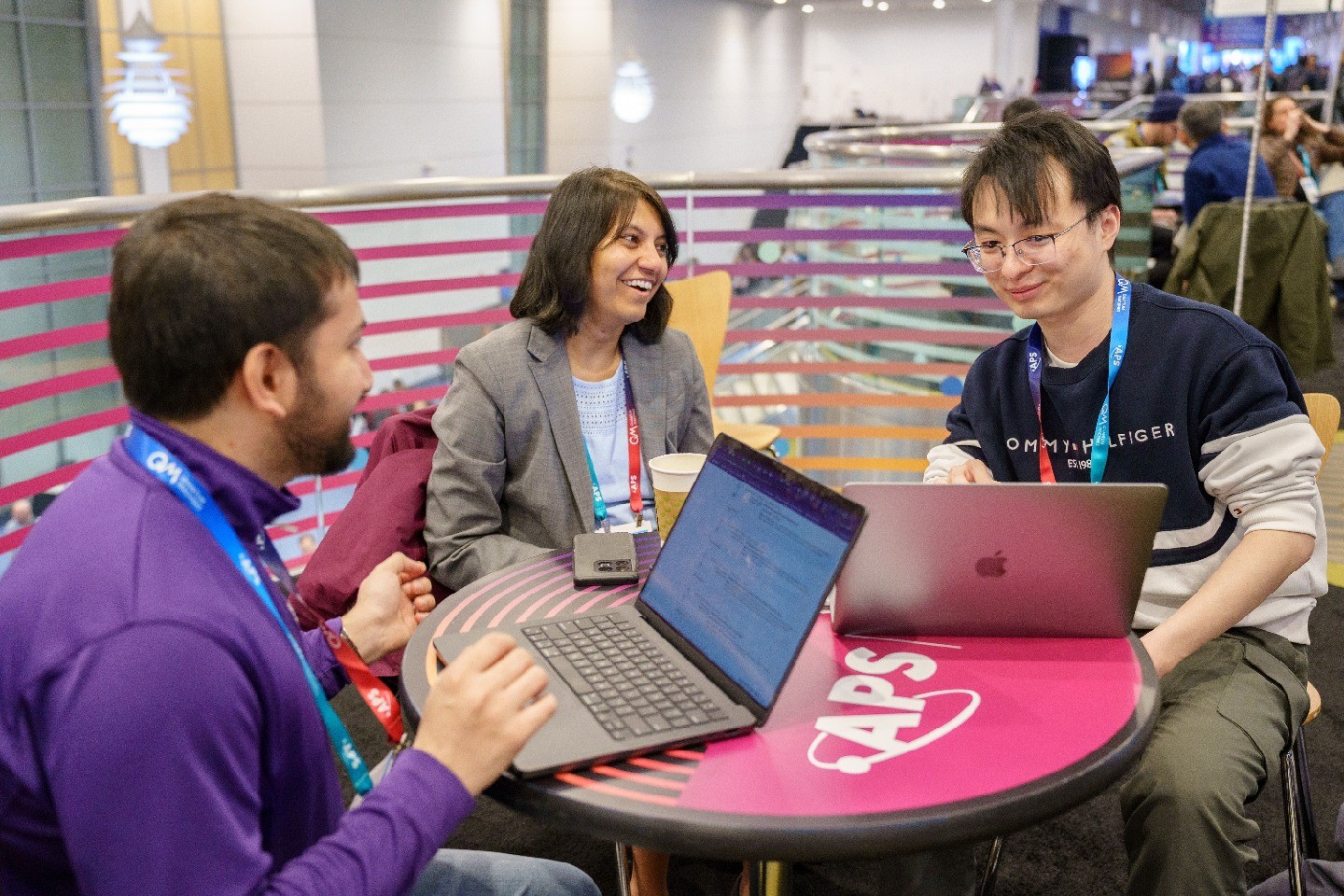 A group of three people sitting around a table with their laptops open