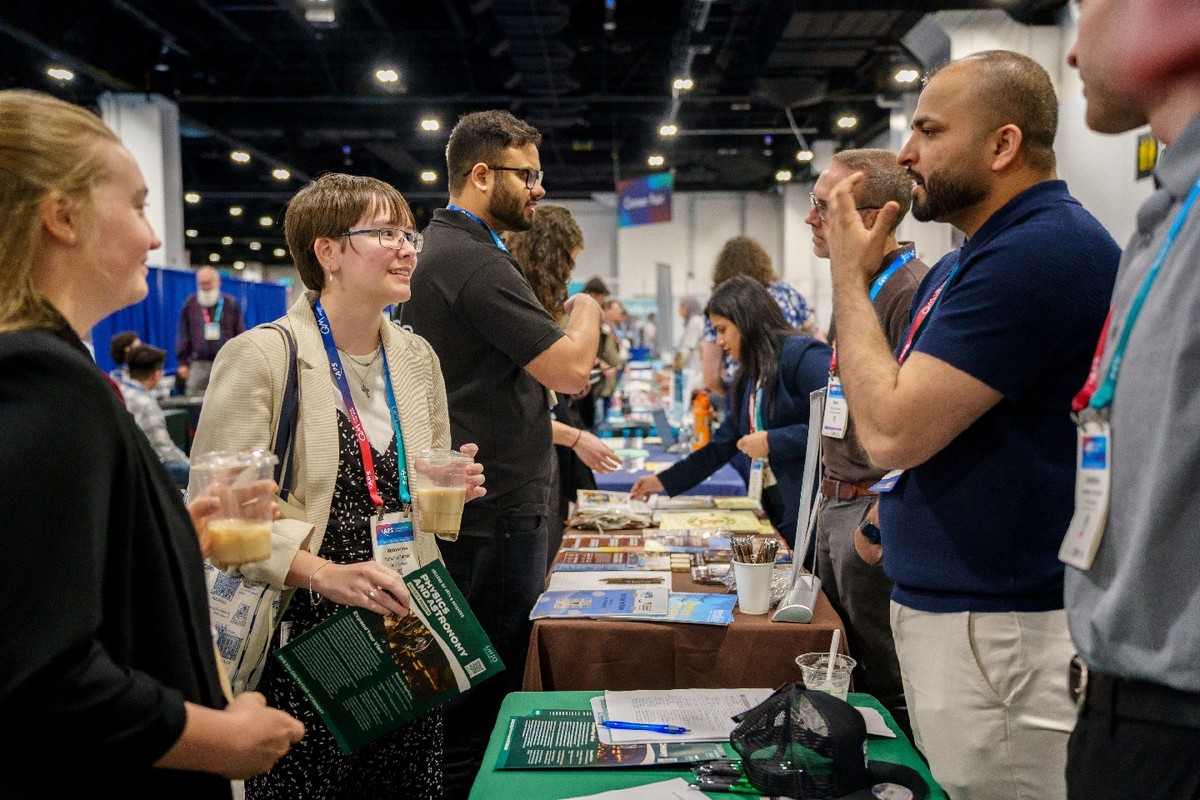 Conference attendees standing at a table and talking with exhibitors.