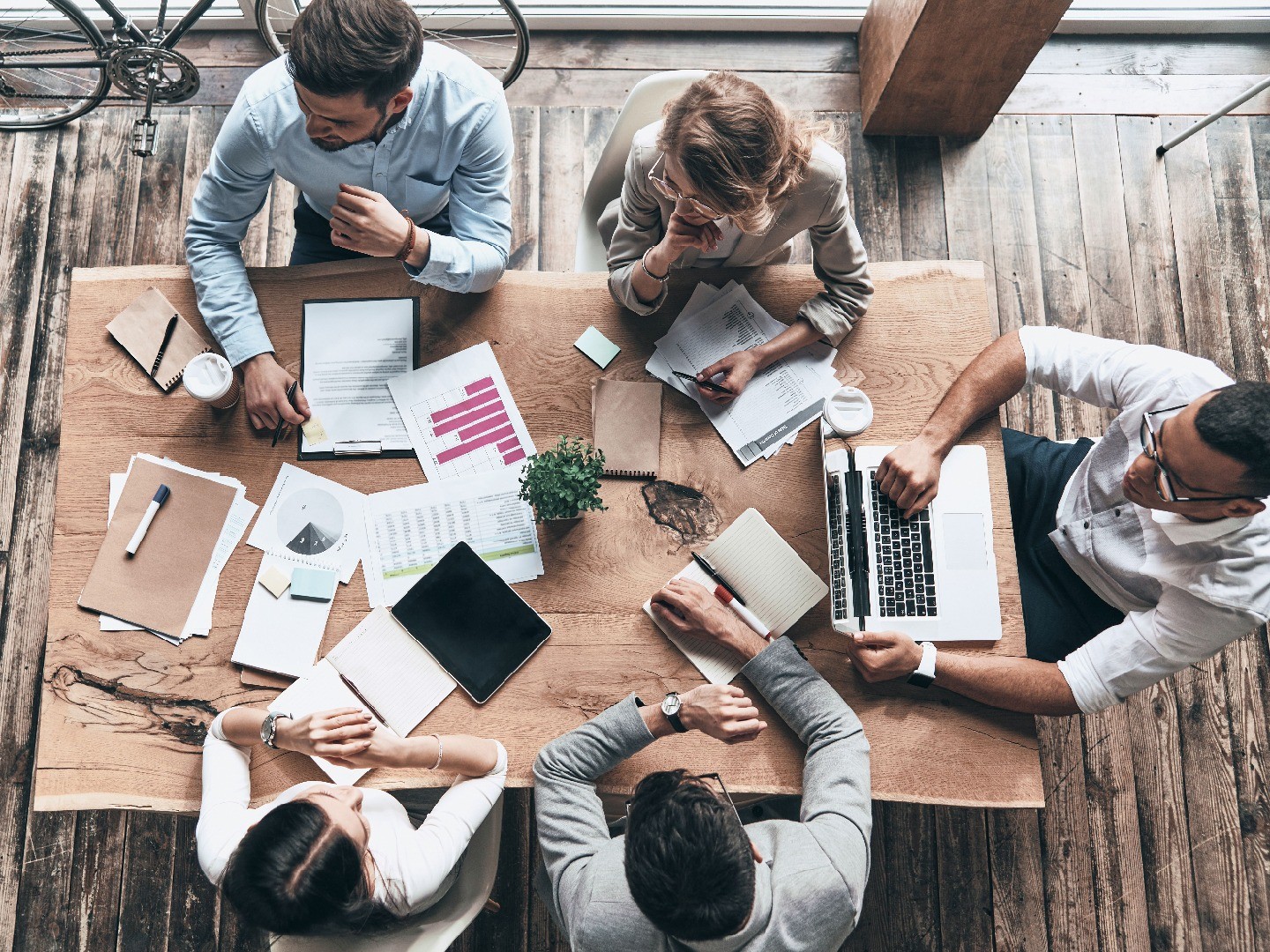 A panel of experts review materials on a large desk.