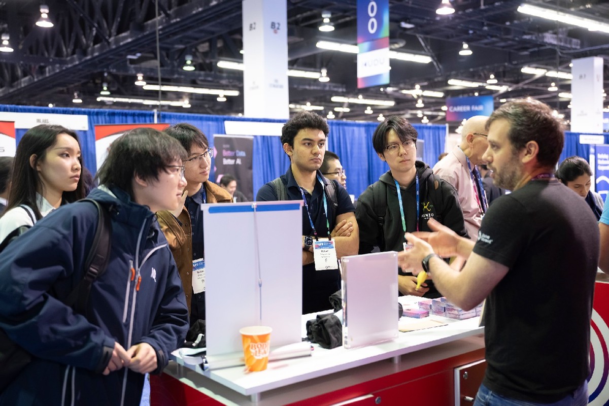 A group of students and scientists speaking with an exhibitor at the APS Global Physics Summit