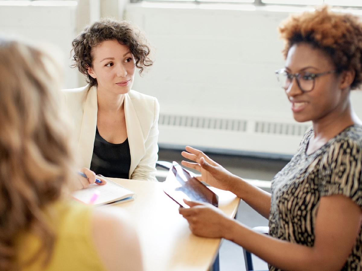 Three racially diverse women sitting around a table together