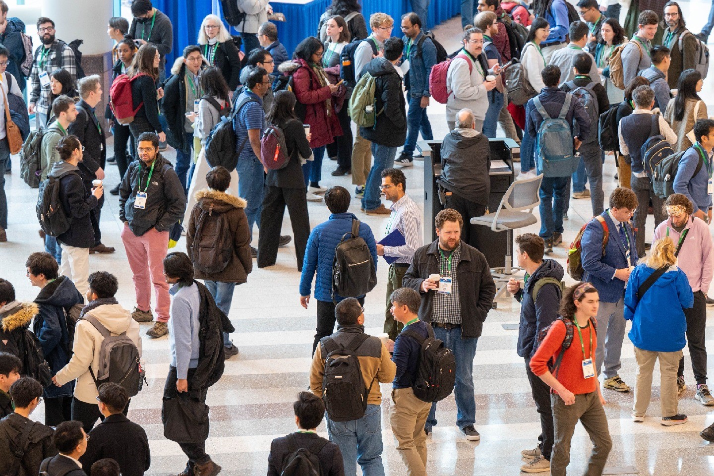 People wearing conference badges and having conversations in a large room.