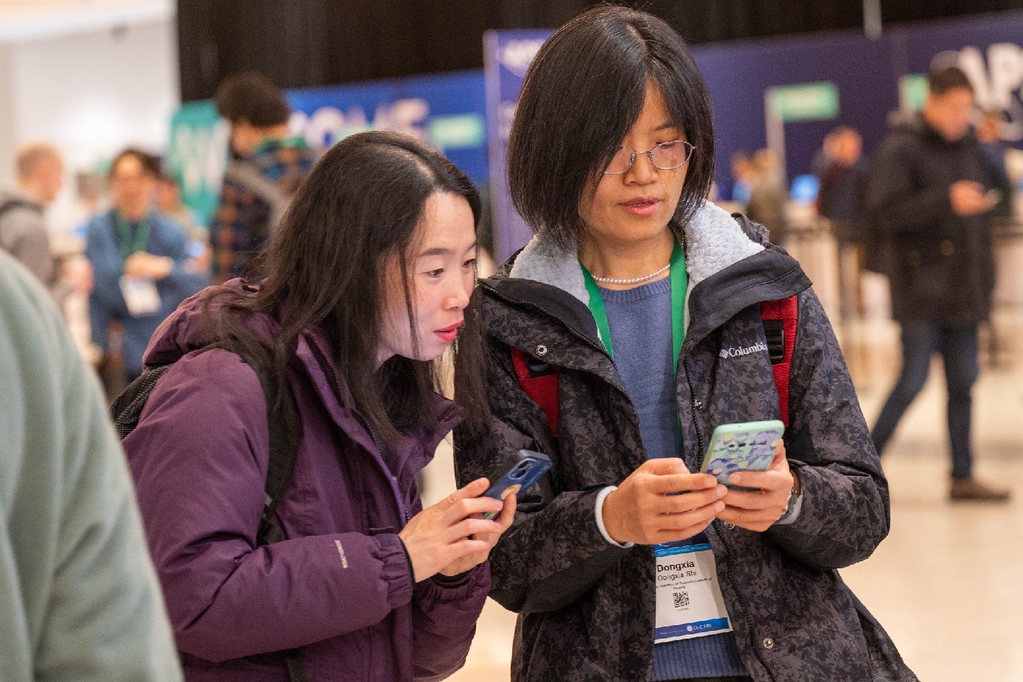 Two people at APS March Meeting looking at a smartphone together