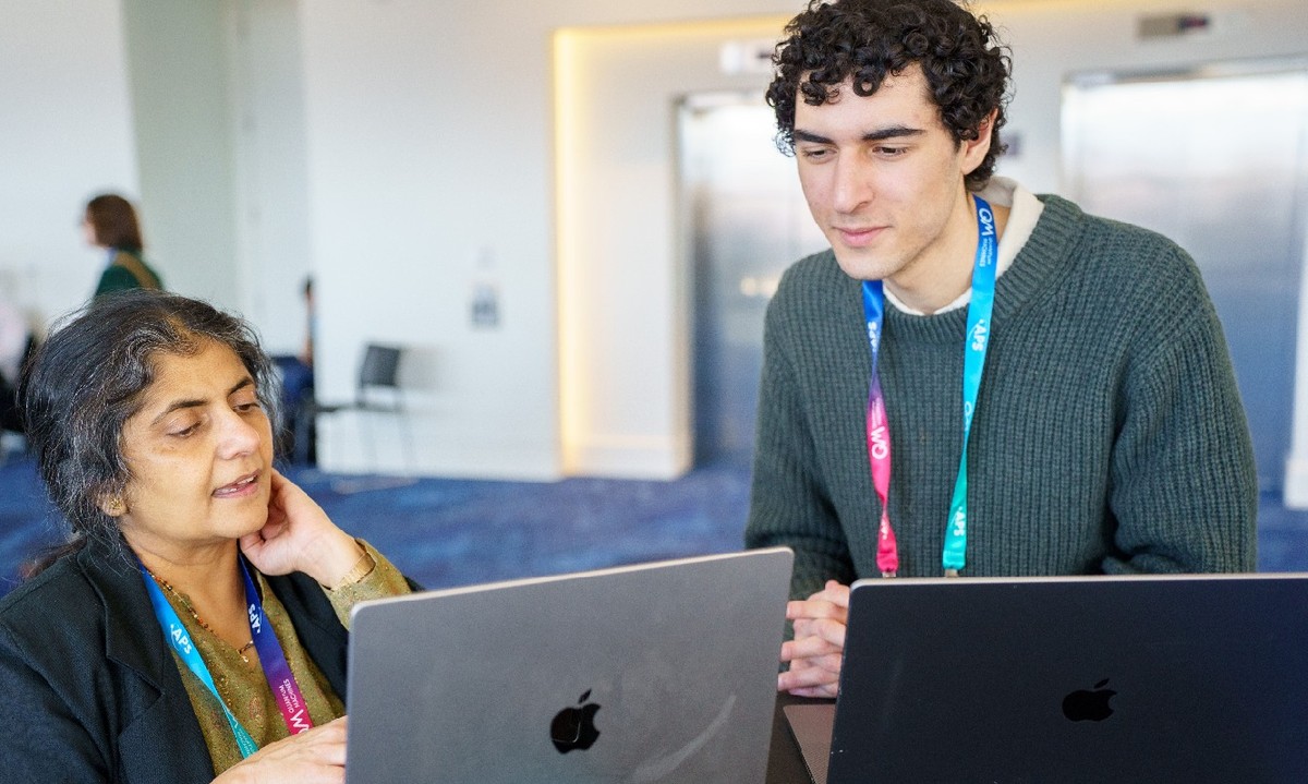 Two physicists looking at laptops together while attending the APS Global Physics Summit