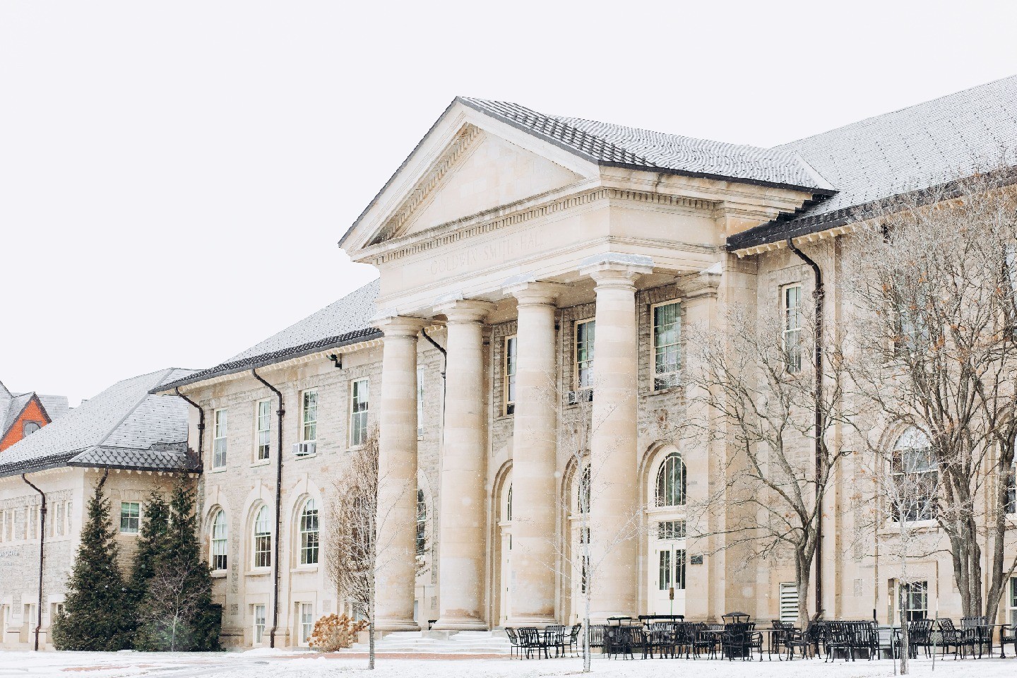 Goldwin Smith Hall, a historic building with dramatic pillars, stands out against a snowy winter sky.
