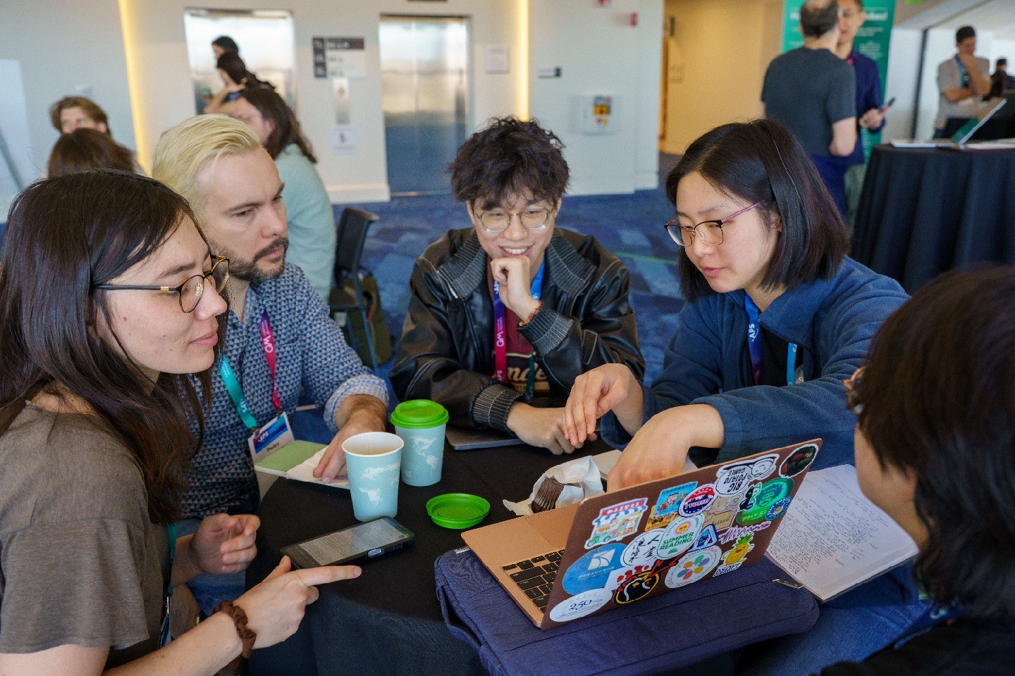 A group of students gathered around a table and looking at a laptop together
