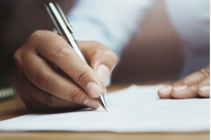 A hand using a pen to write on paper.