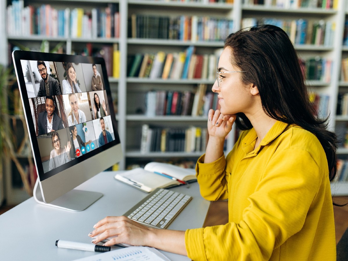 A woman participates in an online meeting on a desktop computer