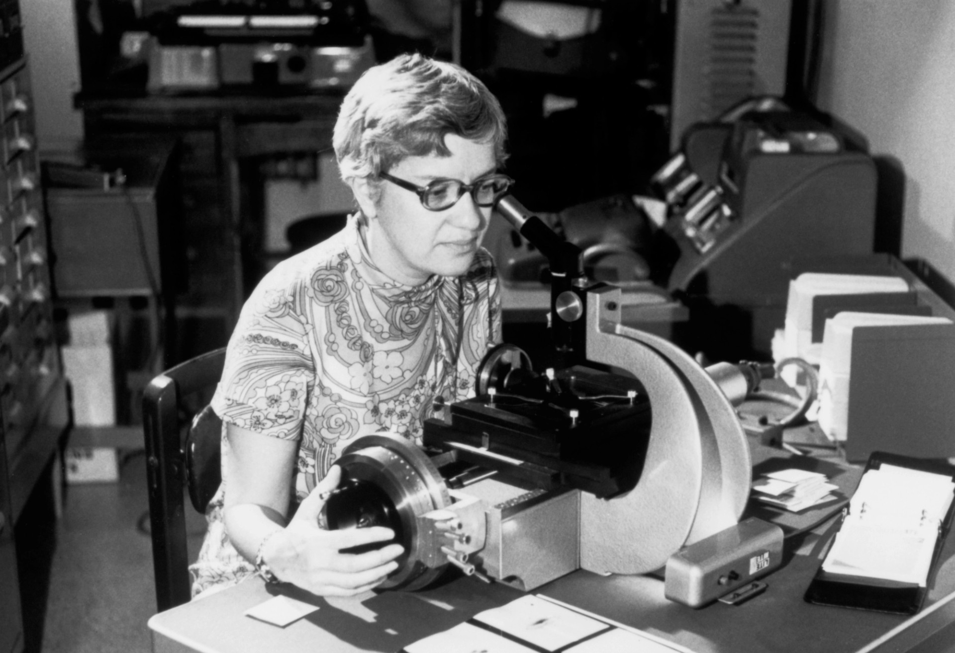 Vera Rubin, wearing a black shirt and black-framed glasses, is smiling while adjusting equipment using Kitt Peak National Observatory's 36-inch telescope with Kent Ford's image tube spectrograph attached.