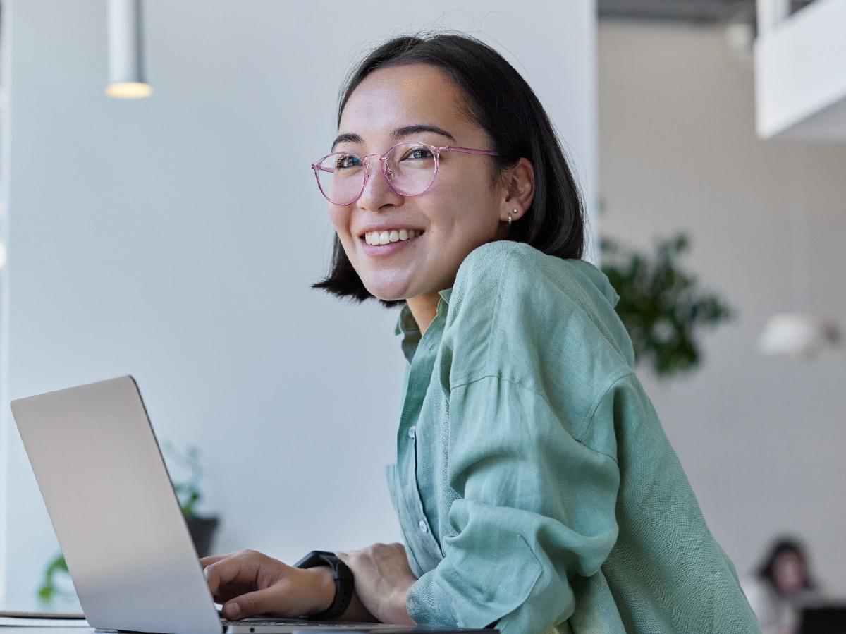 A smiling woman working at a laptop computer