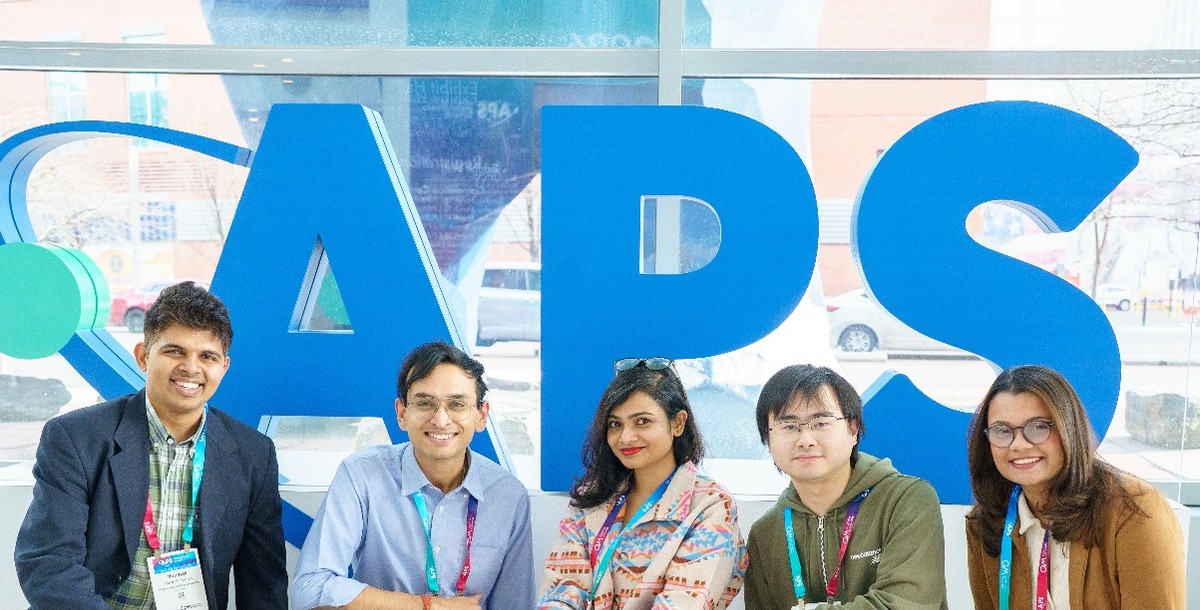 Scientists at the APS Global Physics Summit standing in front of the APS logo