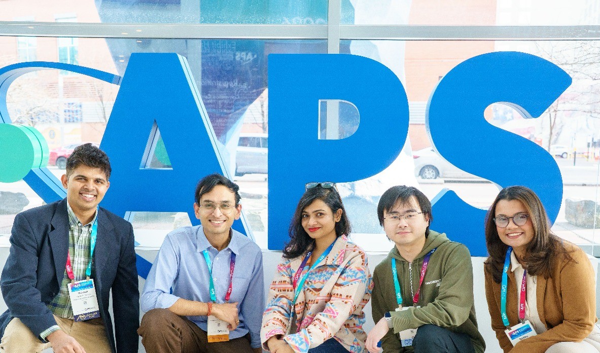 Scientists at the APS Global Physics Summit standing in front of the APS logo