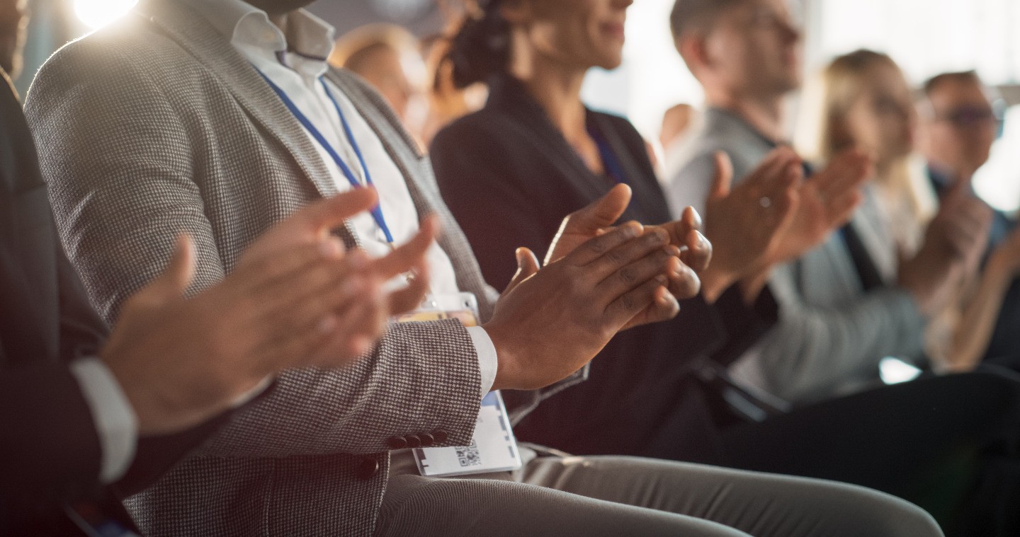 The hands of a seated audience in applause.