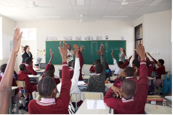 Children raise their hands in a classroom.