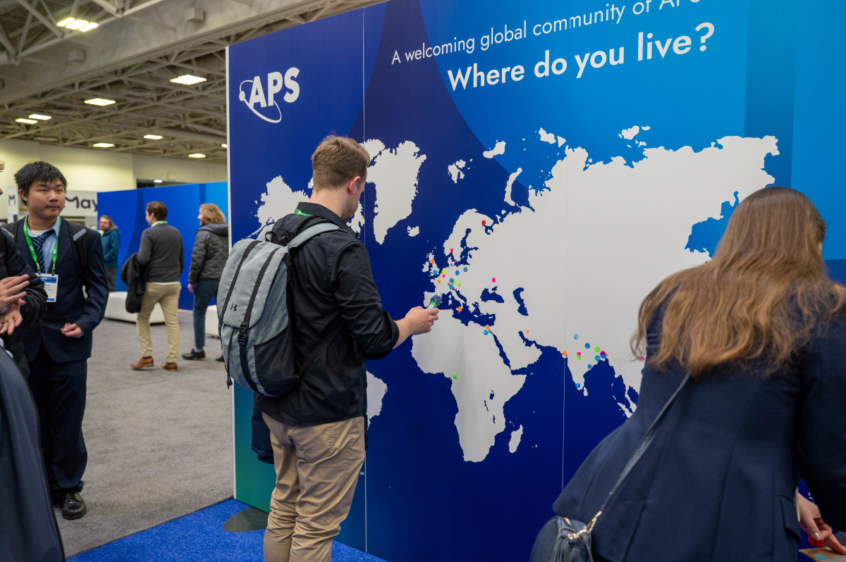 Participants at a conference. One participant is adding a sticker to an APS-branded map.