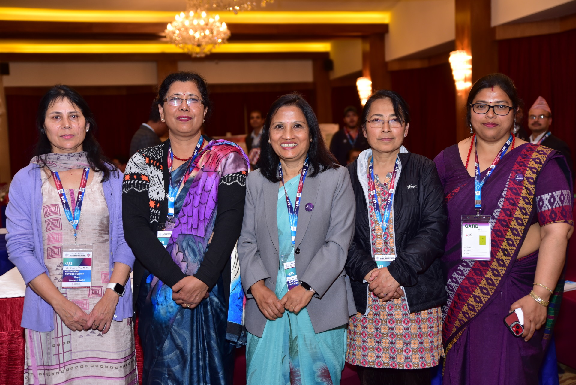Five attendees pose together, smiling and wearing conference badges.