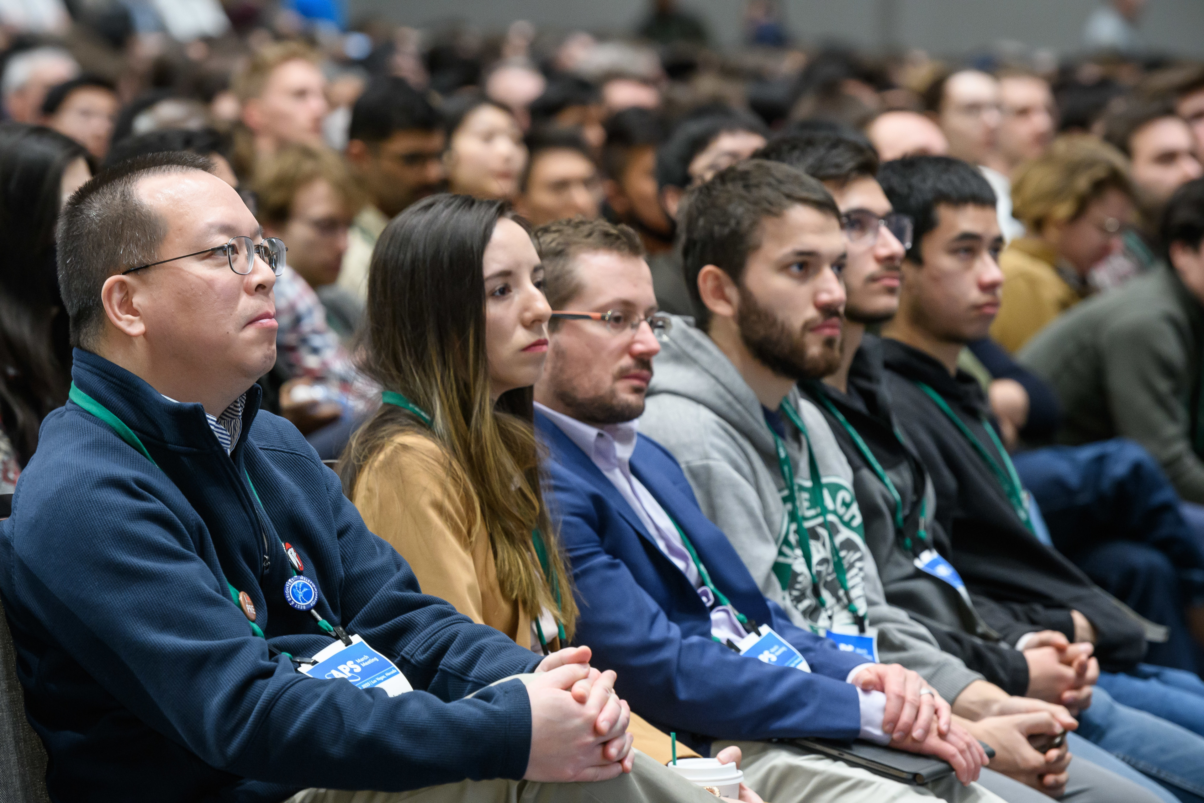 An audience seated and with hands folded in their laps.