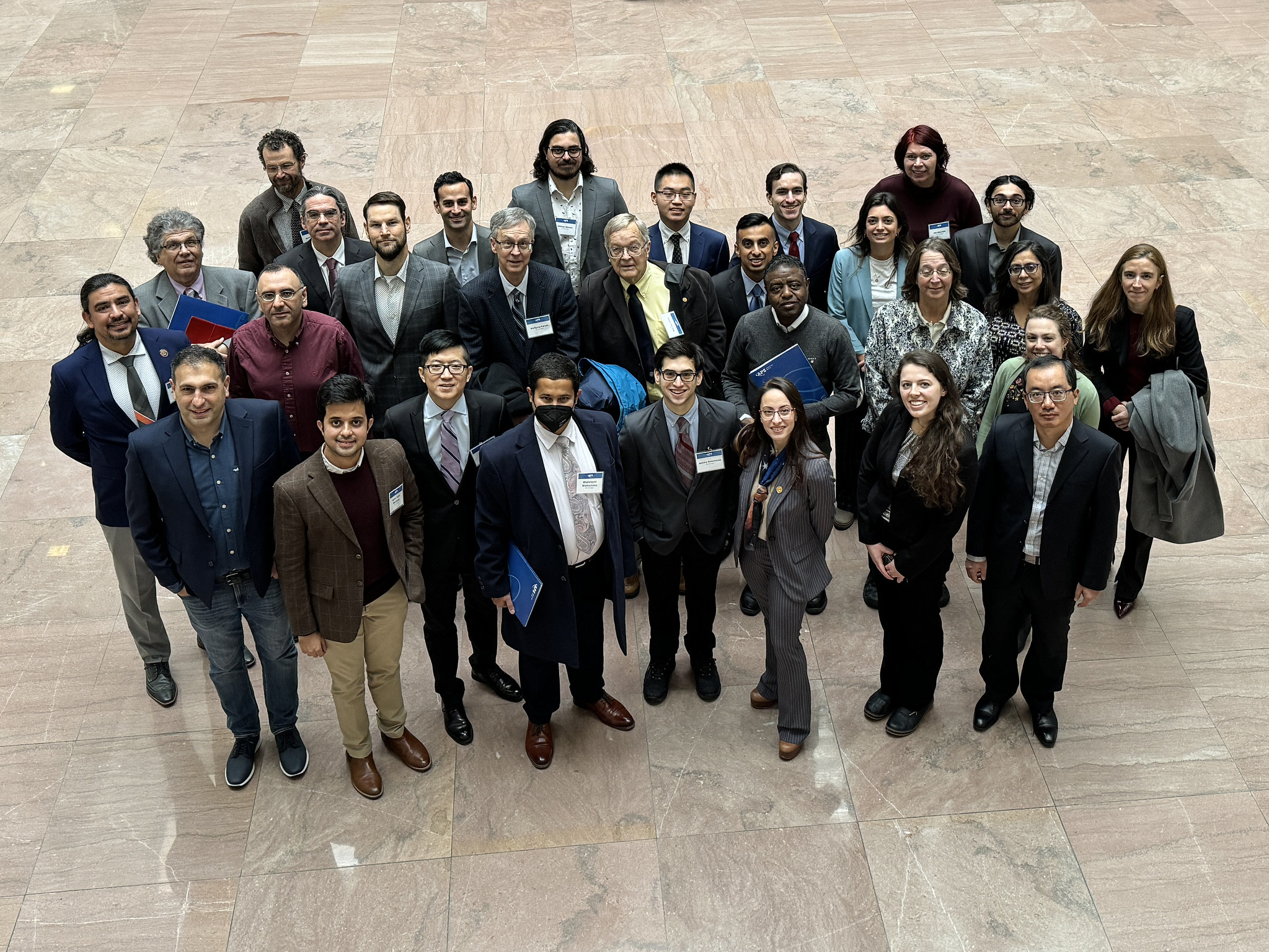 A crowd of people wearing formal clothes looks up at the camera.