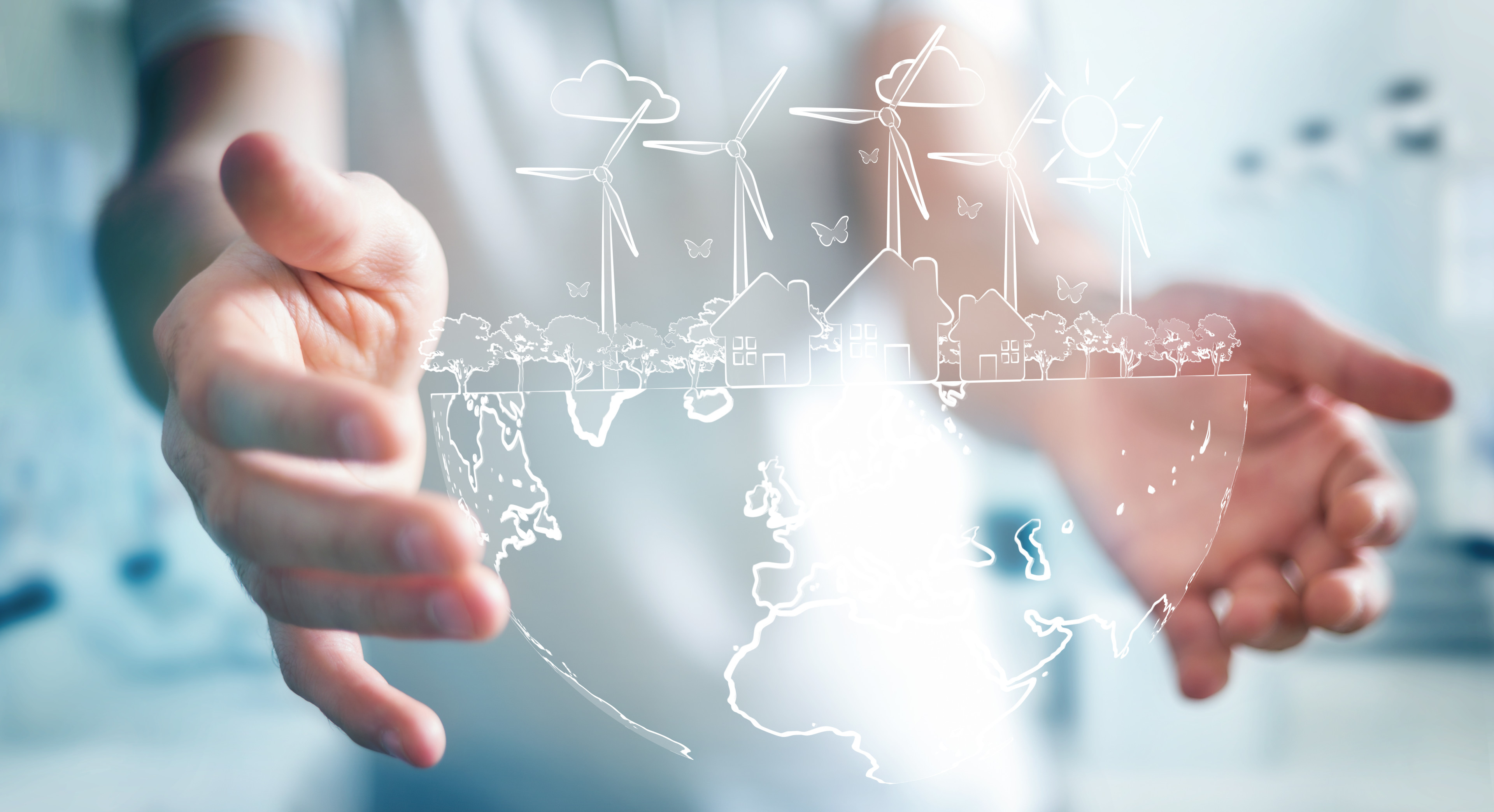 Person holding a translucent earth showing land, windmills, trees, houses, symbolizing a clean and sustainable environment.